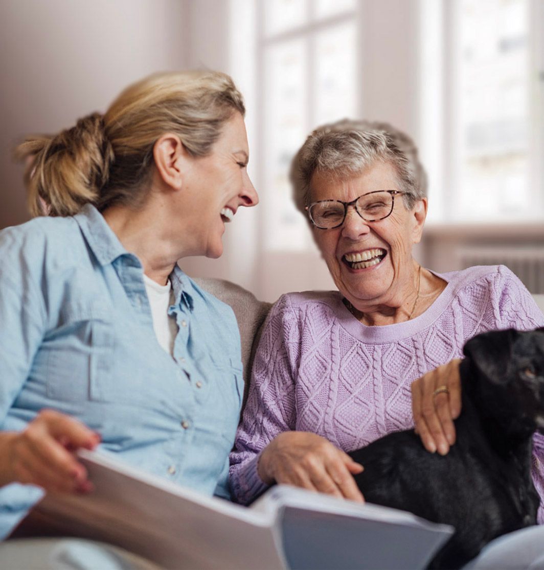Une aide à domicile riant avec une personne âgée